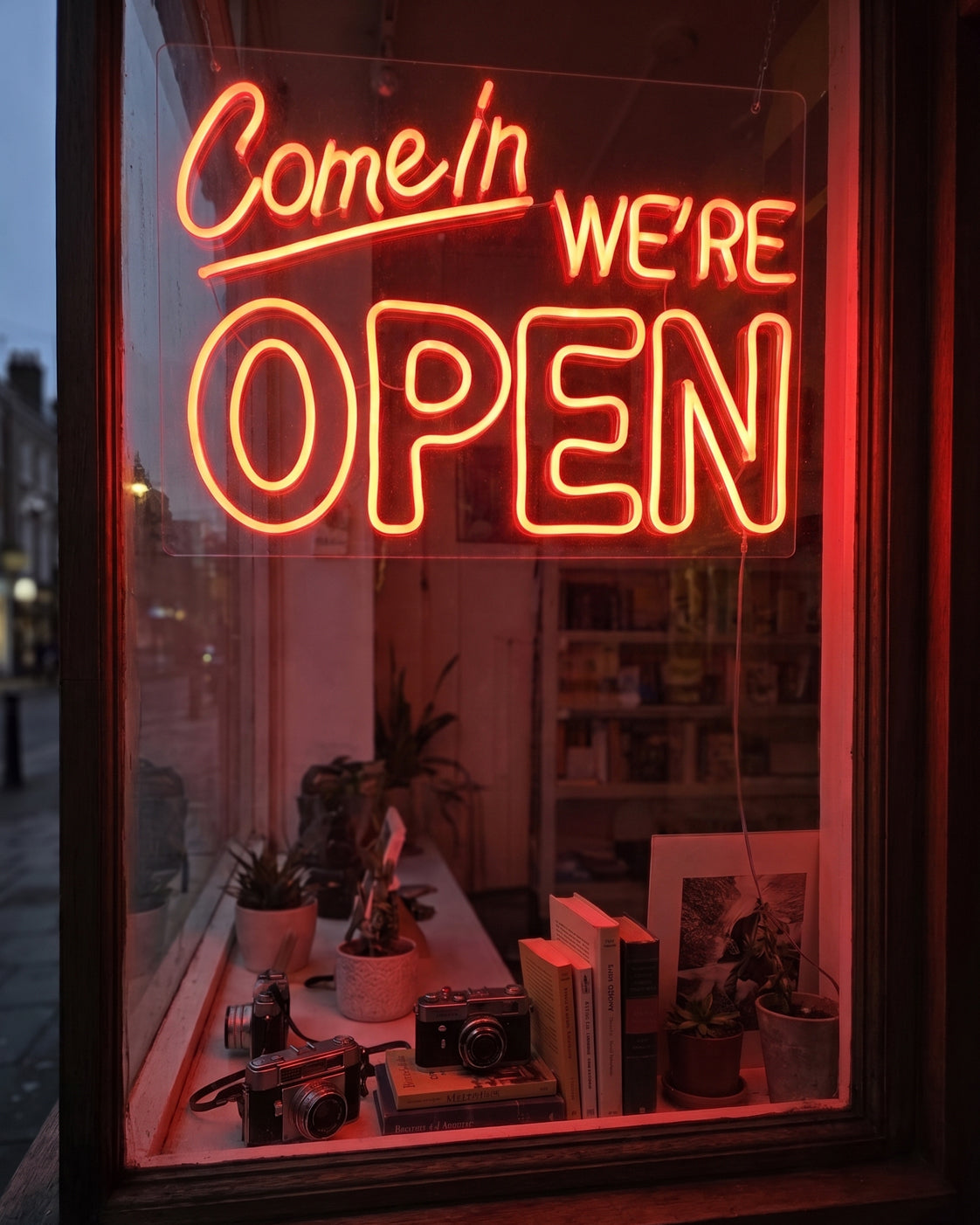 Et neonskilt med teksten «Come in, we're open» i et butikkvindu.